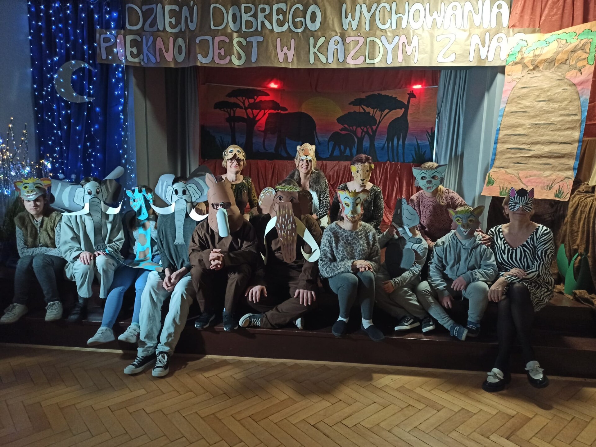 Gupa uczniów przebranych w kostiumy zwierząt siedzi na schodach sceny sali teatralnej w ośrodku specjalnym w Bochni.