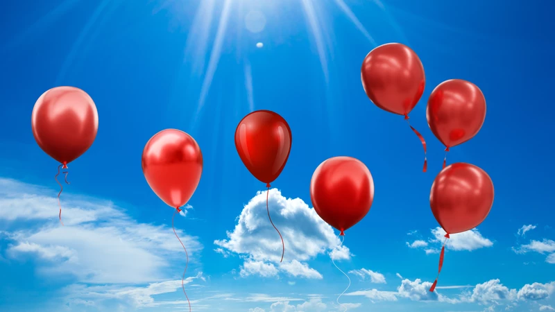 Siedem czerwoych balonów na tle niebieskiego nieba.
