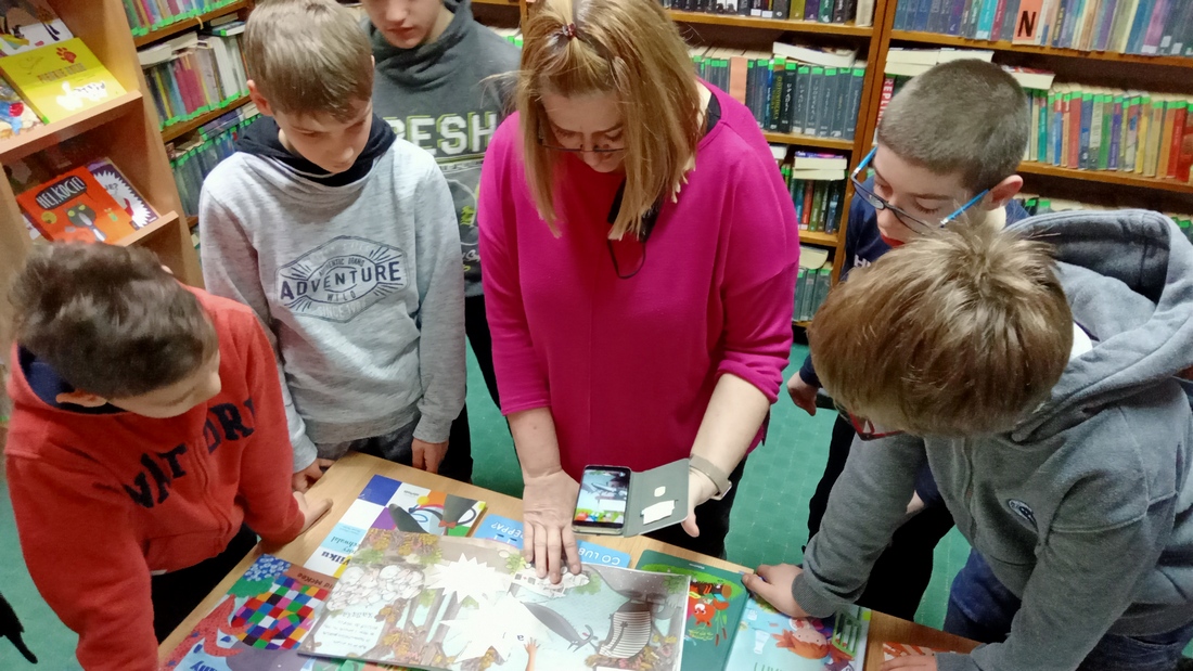 Grupa uczniów przegląda książki w bibliotece.