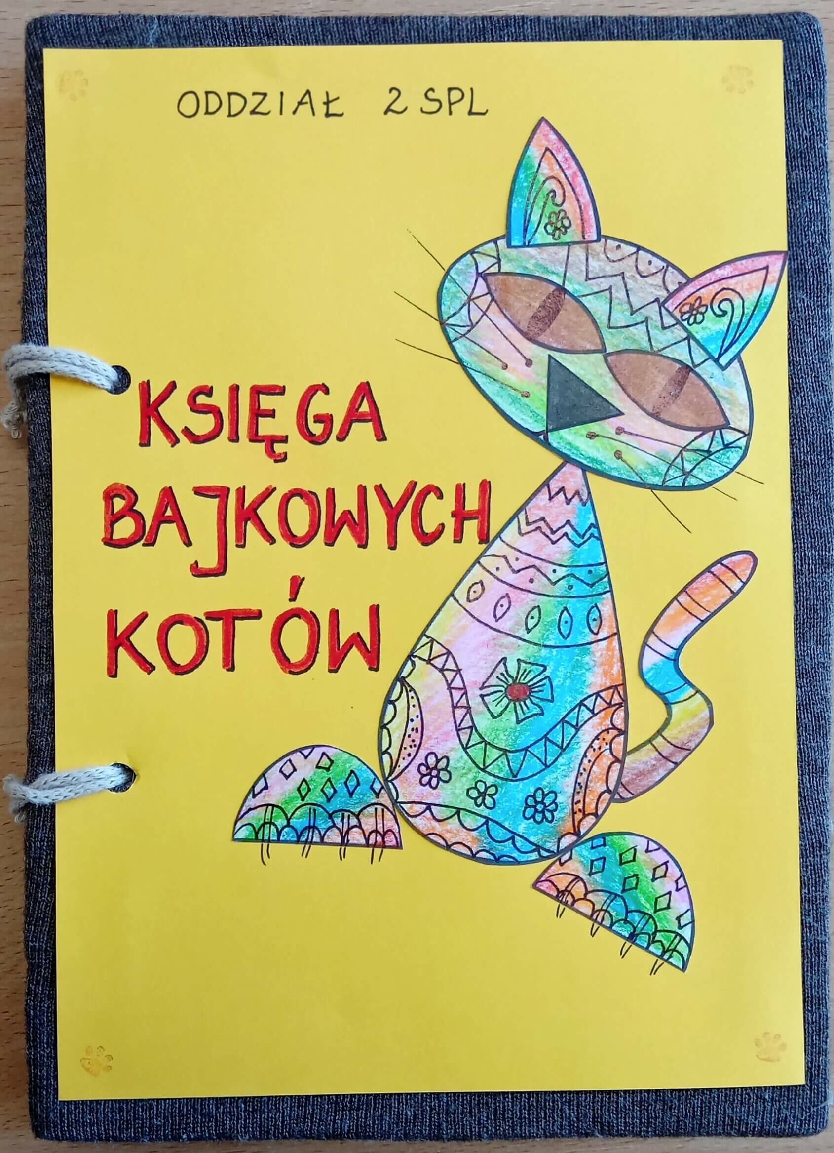 Okłsadka ksiązki w kolorze żółtym i narysowanym kolorowym kotem.