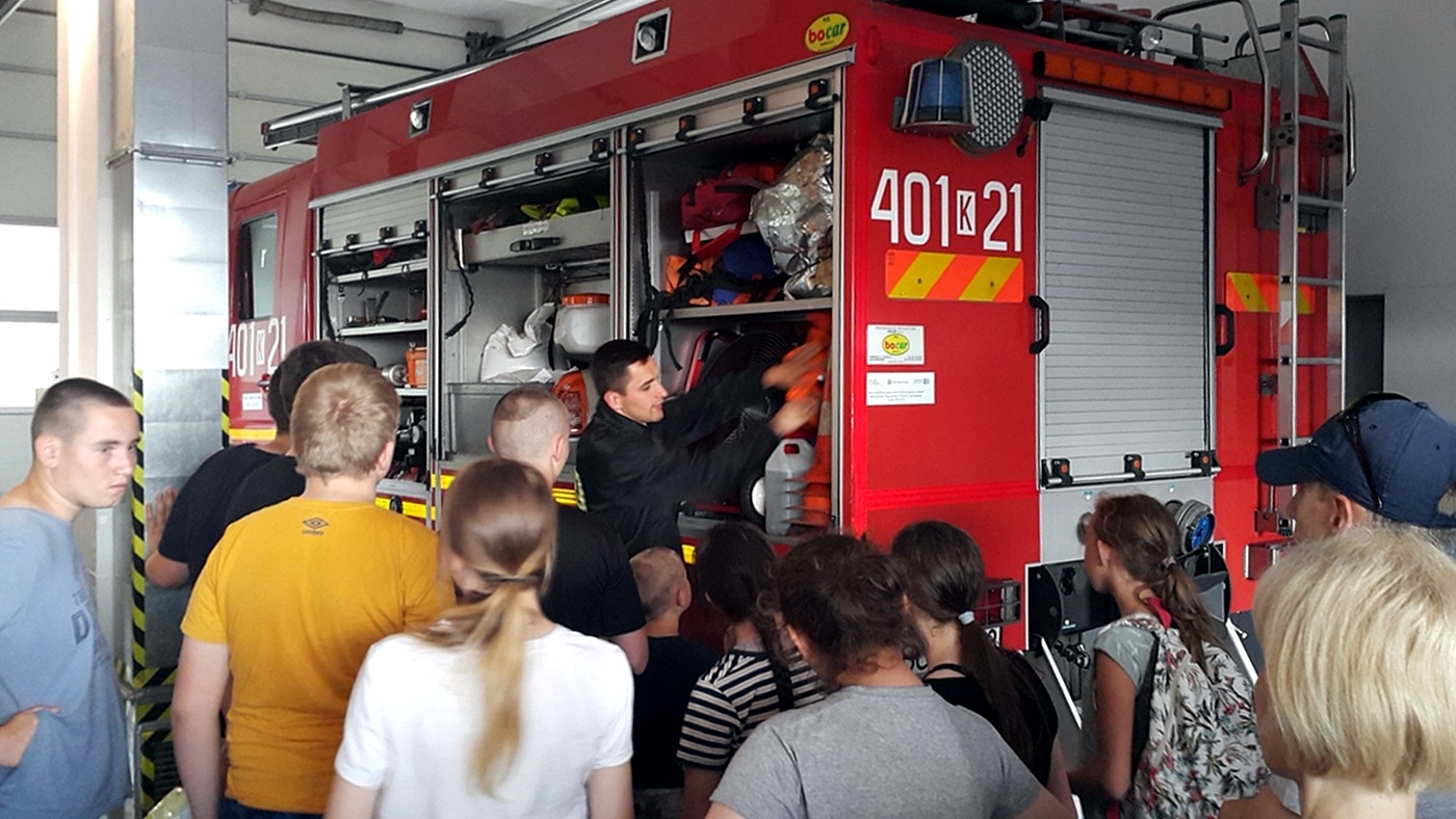 Grupa młodziezy oglada zawartośc sprzętu ratowniczego w wozie strażackim