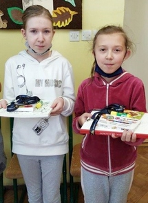 Dwie uczennice trzymają nagrody za konkurs wiedzy na temat odzyskania niepodległości