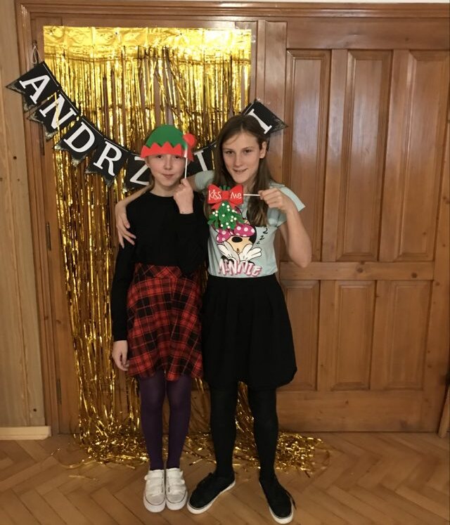 Dwie dziewczynki pozują do zdjęcia na tle napisu Andrzejki.