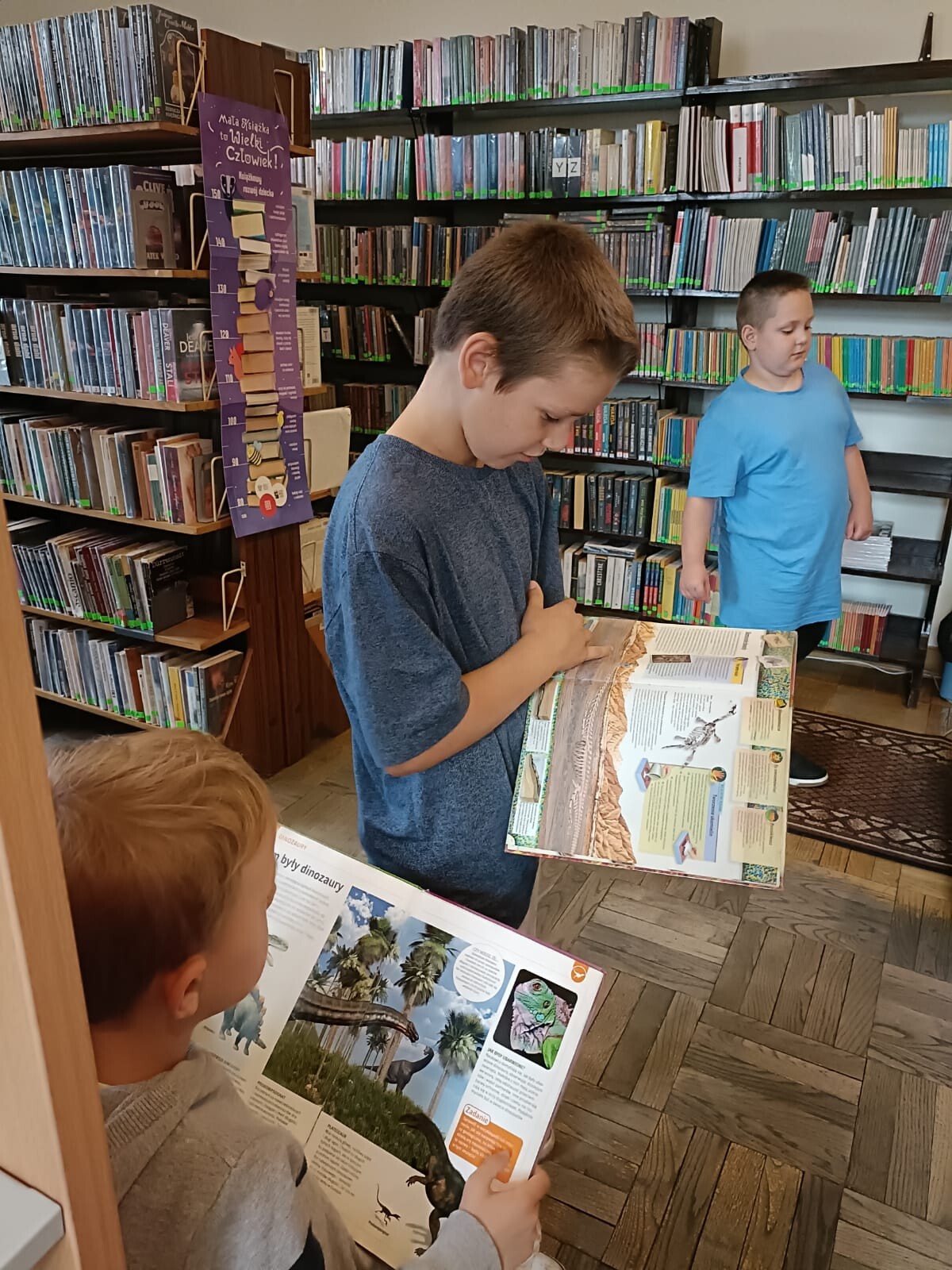 Dwóch chłopców przegląda książki w bibliotece.