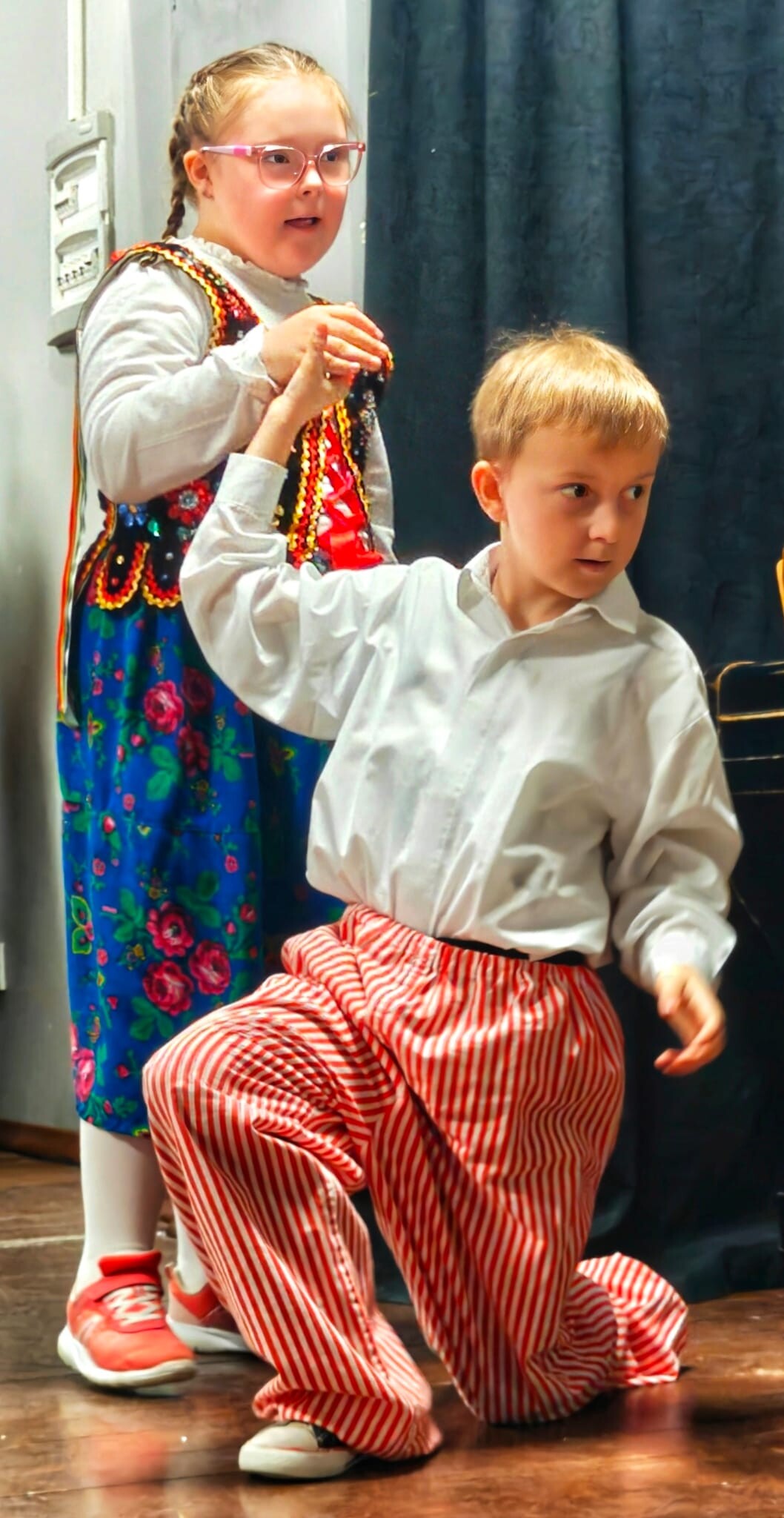 Dziewvzynka i chłopiec ubrani w stroje krakowskie tańczą karakowiaka.