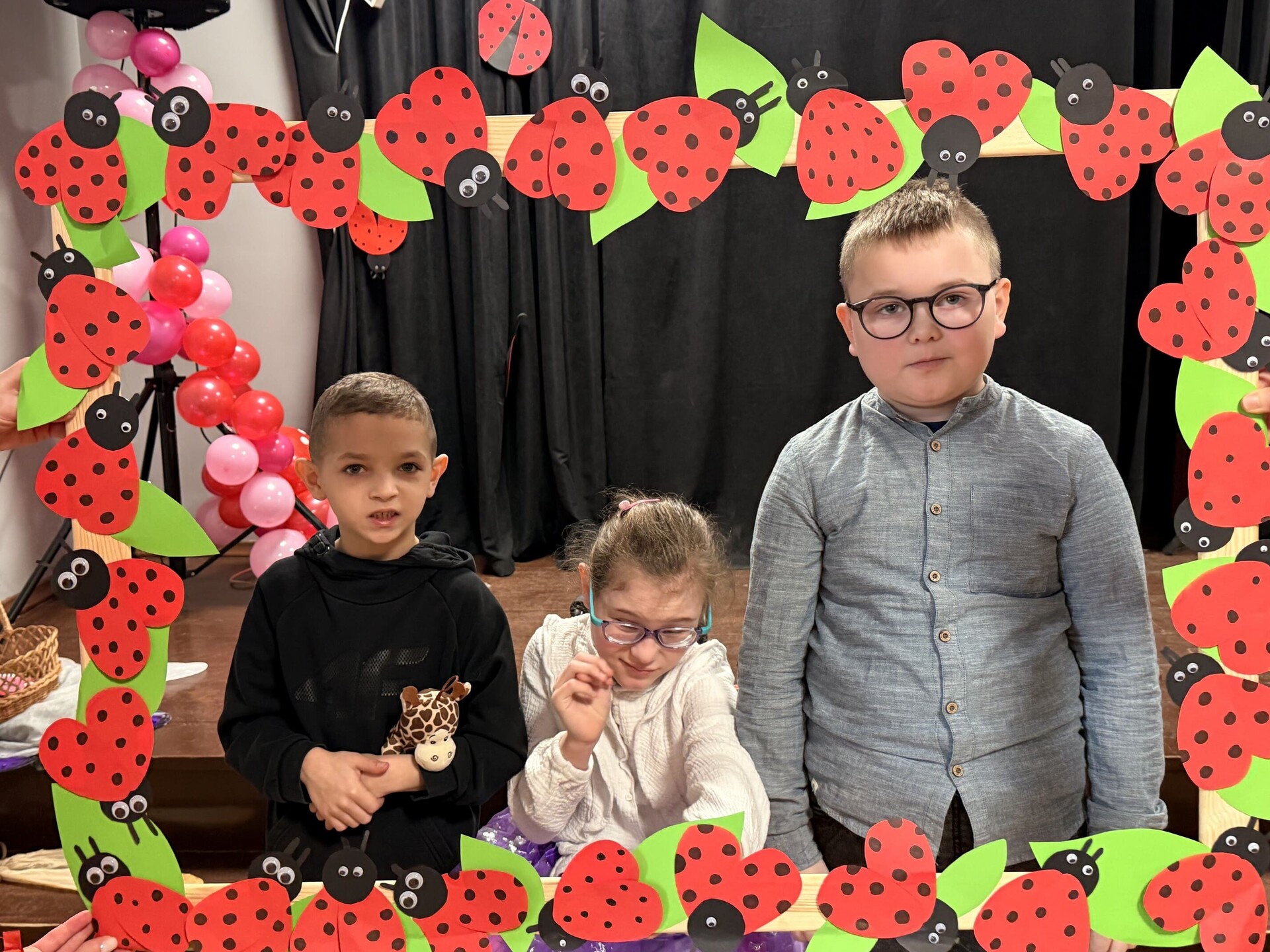 Troje uczniów pozuje do zdjęcie w fotoramce.