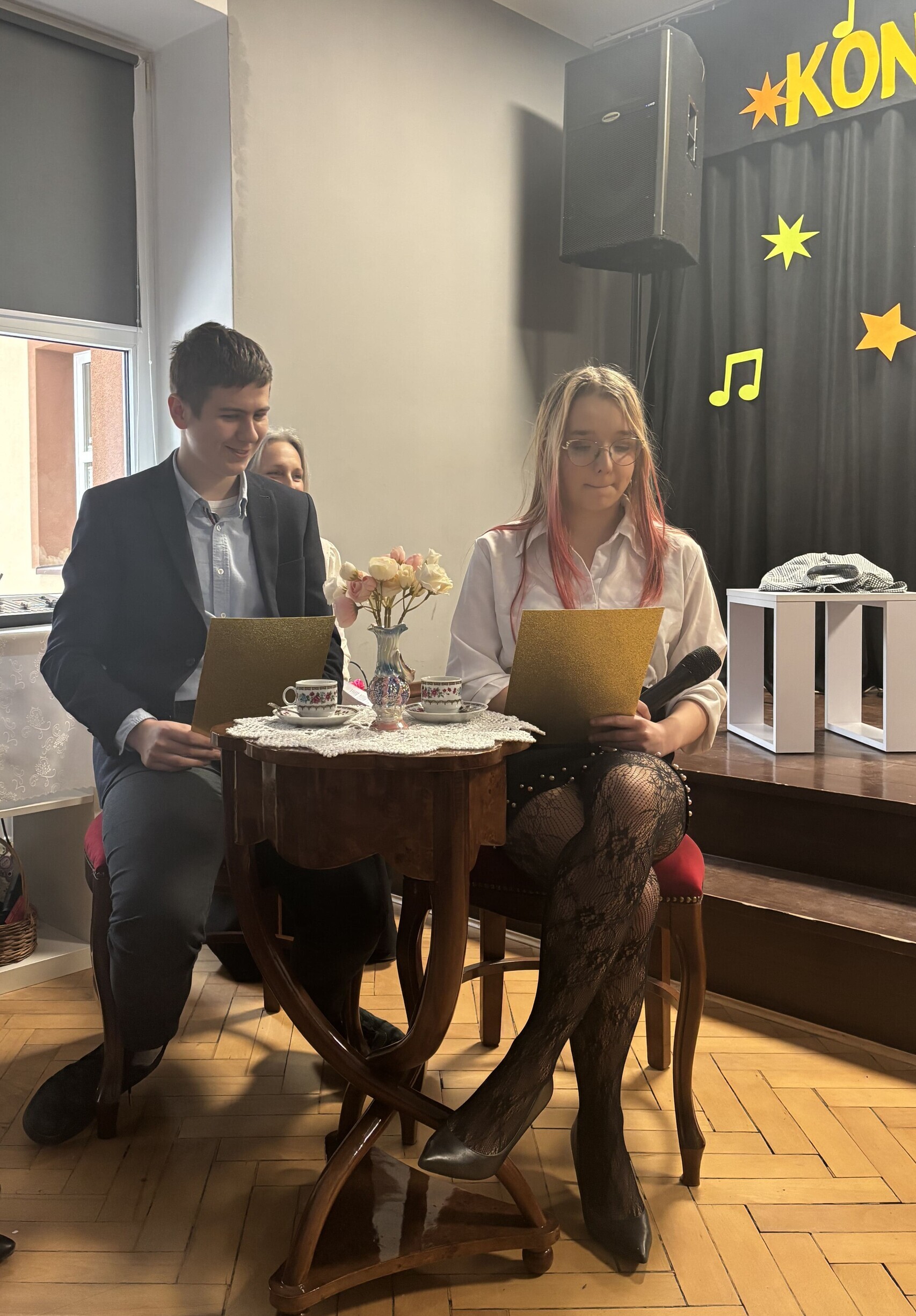 Chłopiec i dziewczyna siedzą przy stoliku i czytają życzenia.