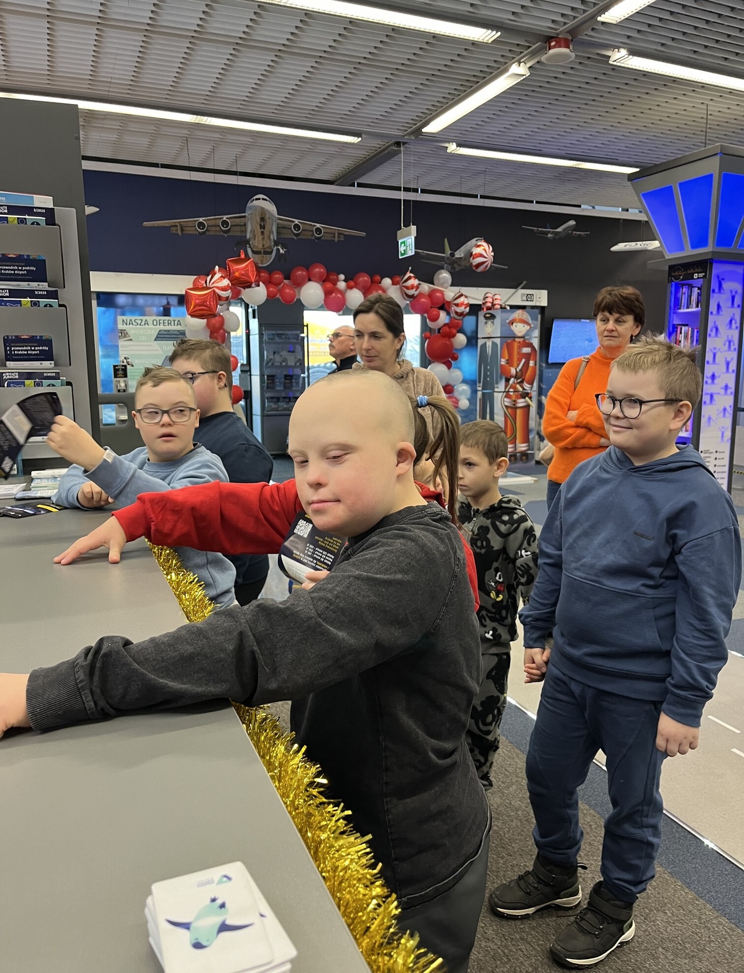 Grupa uczniów w Centrum Edukacji Lotniczej w Krakowie zwiedza lotnisko.