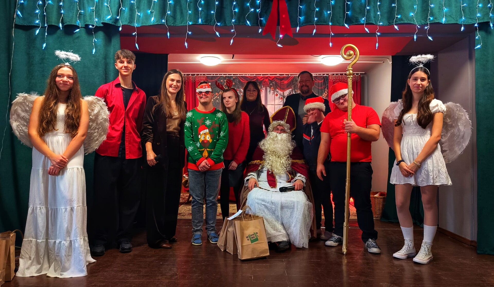 Grupa uczniów i nauczycieli stoją przy siedzącym na krześle  Świętym Mikołu.