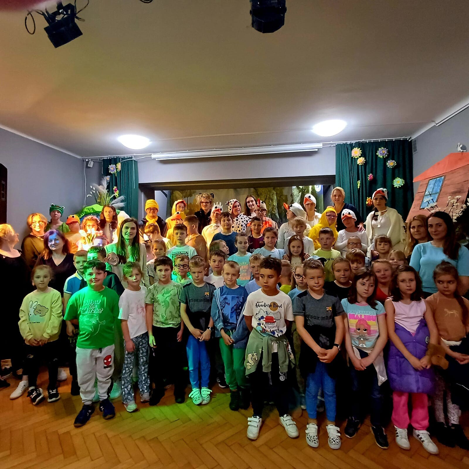 Duża grupa uczniów pozuje do zdjęcia w sali szkolnej.