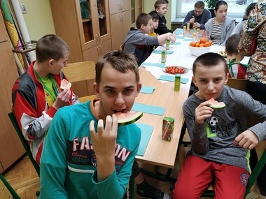 Na zdjęciu chłopcy jedzący arbuza