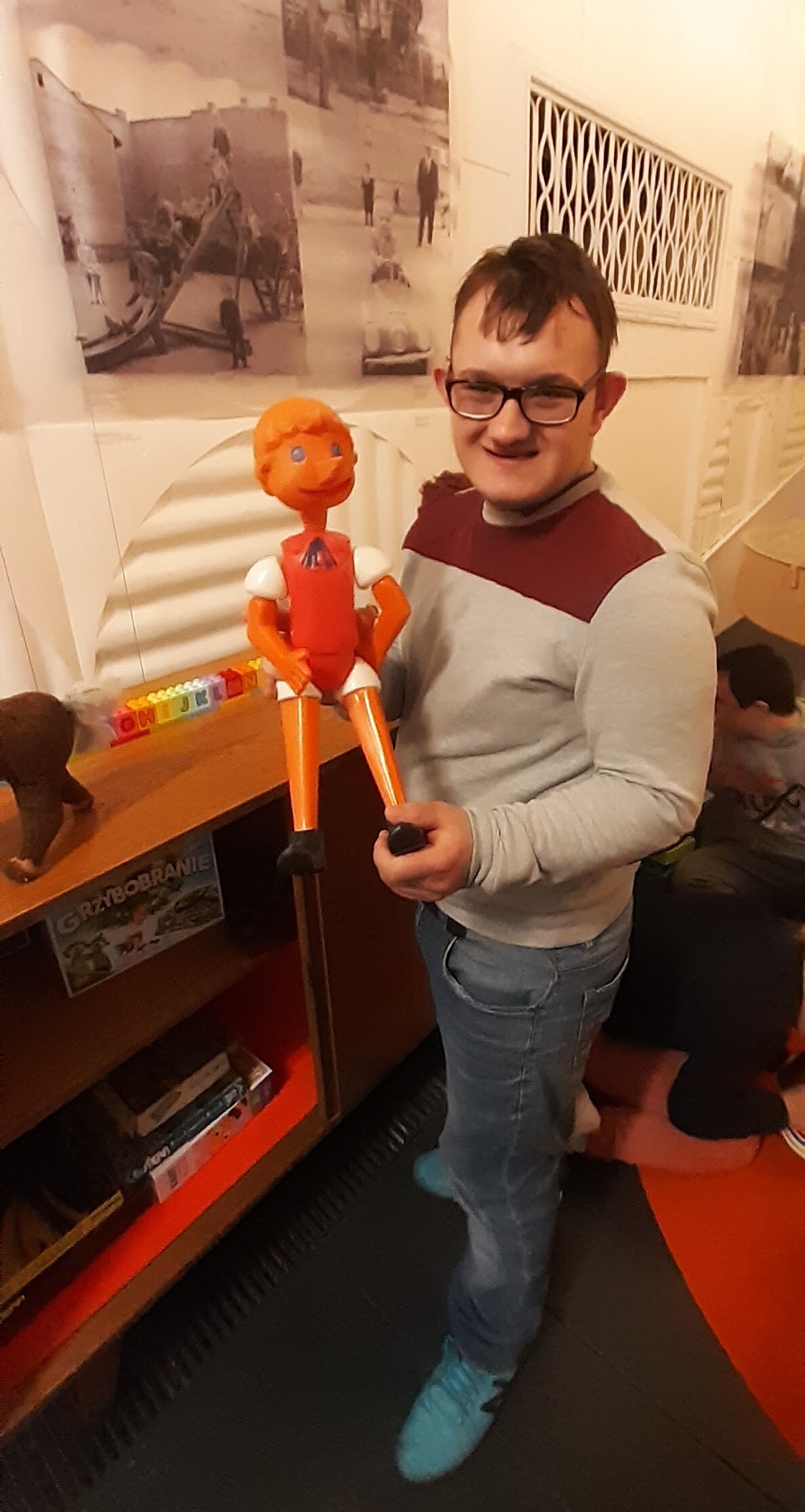 Chłopiec w okularach prezentuje maskotkę Pinokia w Muzeum Nowej Huty w Krakowie.