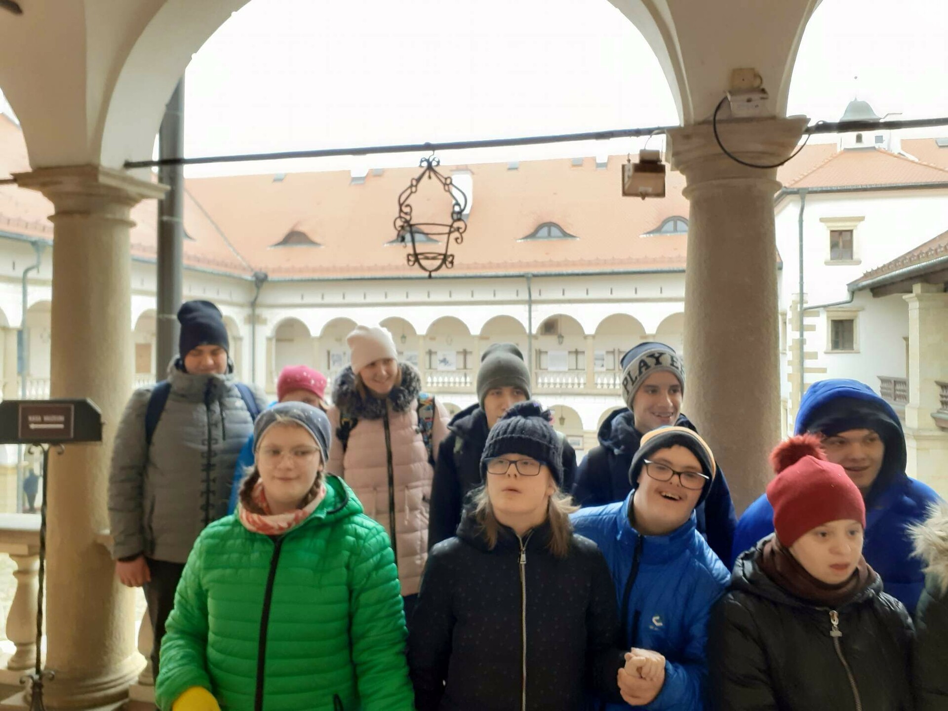 Grupa młodzieży pozuje do zdjęcia na dziedzińcu zamkowym w Niepołomicach.