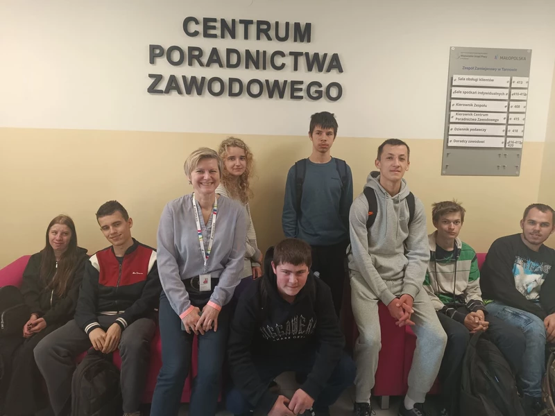 Młodzież szkolna siedzi na krzesłach w holu Wojewódzkiego Urzędu Pracy.