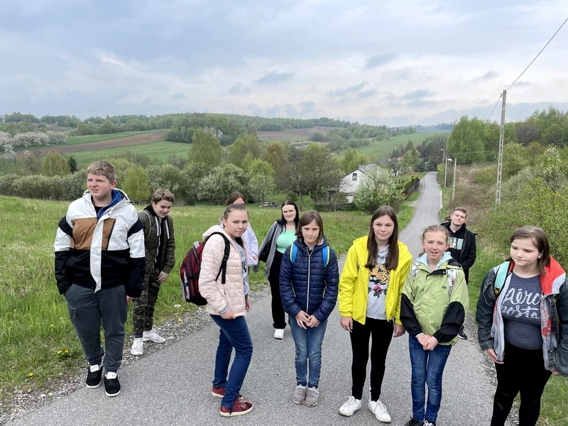 Grupa dziewcząt i chłopców pozuje do zdjęcia na tle krajobrazu wyżynnego.