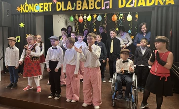 Uczniowie przebrani w stroje krakowskie występują na scenie.