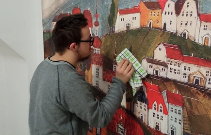 Chłopiec przeciera szmatką fragment przyklejonej fototapety.