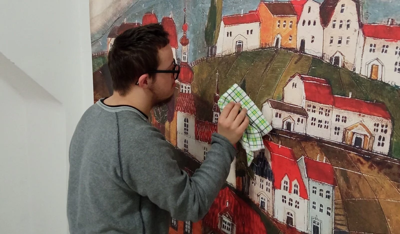 Chłopiec przeciera szmatką fragment przyklejonej fototapety.