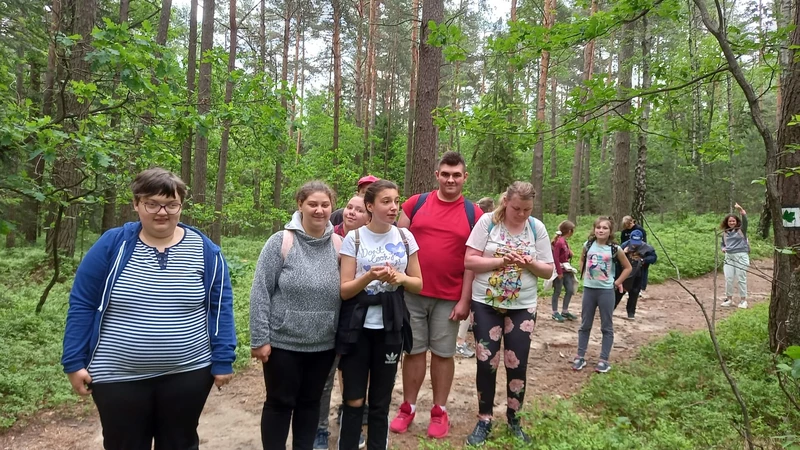 Grupa uczniów pozuje do zdjęcia na leśnej ścieżce.