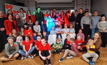 Uczniowie siedzą na schodach sceny  w sali teatralnej SOSW i pozują do zdjęcia.