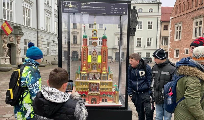 Grupa uczniów stoi przy szklanej gablocie, w której umieszczona jest szopka krakowska.