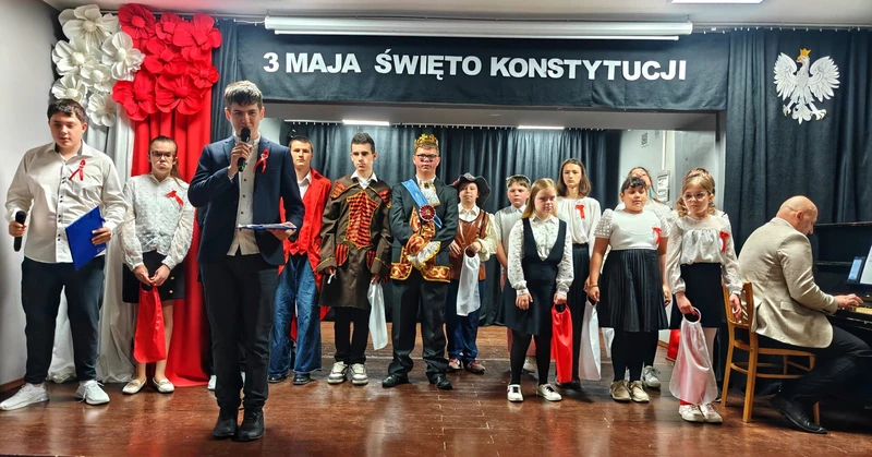 Uczniowie ubrani na galowo, wystepują na akademii z okazji rocznicy uchwalenia Konstytucji  3 maja.