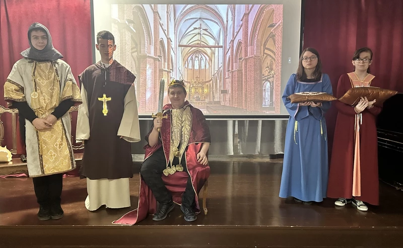 Uczniowie przebrani w stroje królewskie z czasów Bolesława Chrobrego występują na scenie.