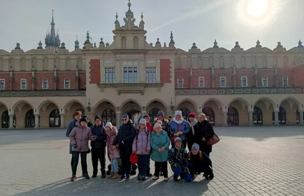 Grupa młodzieży pozuje do zdjęcia na tle Krakowskich Sukiennic.