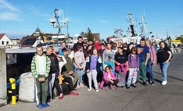 Grupa uczniów stoi na nadbrzeżu w Łebie.