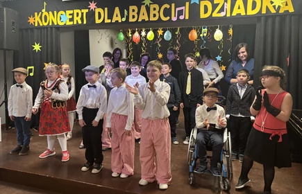 Uczniowie przebrani w stroje krakowskie występują na scenie.