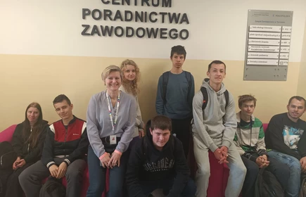 Młodzież szkolna siedzi na krzesłach w holu Wojewódzkiego Urzędu Pracy.