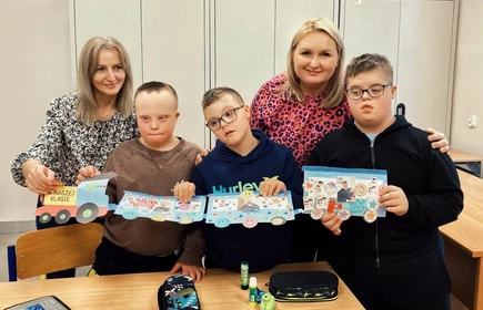 Uczniowie z nauczycielem prezentują pociąg wykonany z tektury.