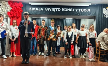 Uczniowie ubrani na galowo, wystepują na akademii z okazji rocznicy uchwalenia Konstytucji  3 maja.