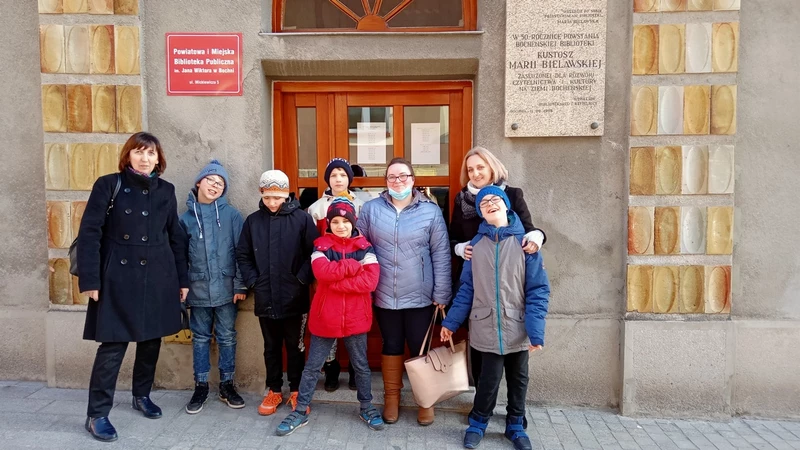 Grupa uczniów stoi przed wejściem do Publicznej Biblioteki w Bochni