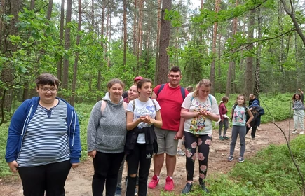 Grupa uczniów pozuje do zdjęcia na leśnej ścieżce.