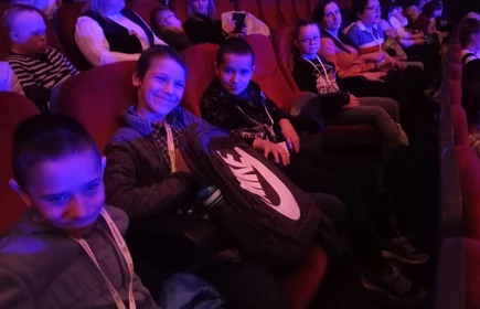 Dzieci siedzą na widowni w teatrze, światło jest już przygaszone.
