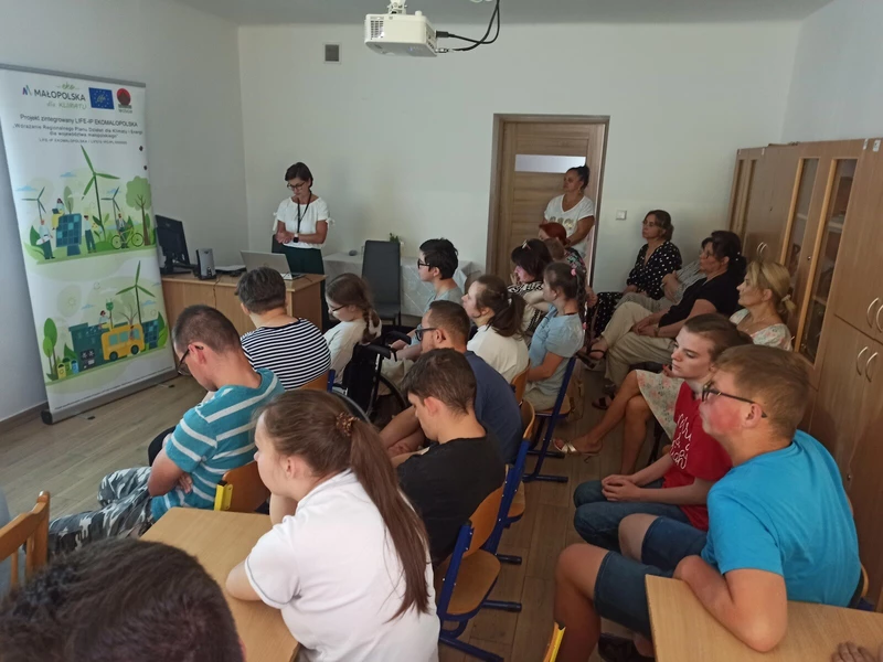 Grupa uczniów słucha wykładu.