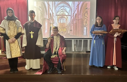 Uczniowie przebrani w stroje królewskie z czasów Bolesława Chrobrego występują na scenie.
