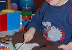 Na zdjęciu mały chłopieć grający na dziecięcym ksylofonie