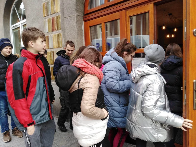 Grupa młodzieży wchodzi do budynku Biblioteki Publicznej w Bochni.