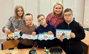 Uczniowie z nauczycielem prezentują pociąg wykonany z tektury.