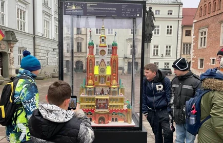 Grupa uczniów stoi przy szklanej gablocie, w której umieszczona jest szopka krakowska.