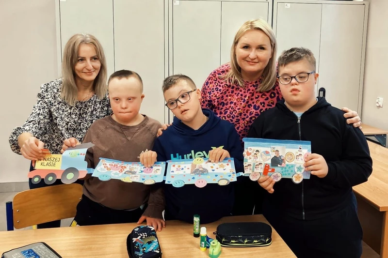 Uczniowie z nauczycielem prezentują pociąg wykonany z tektury.