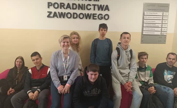 Młodzież szkolna siedzi na krzesłach w holu Wojewódzkiego Urzędu Pracy.